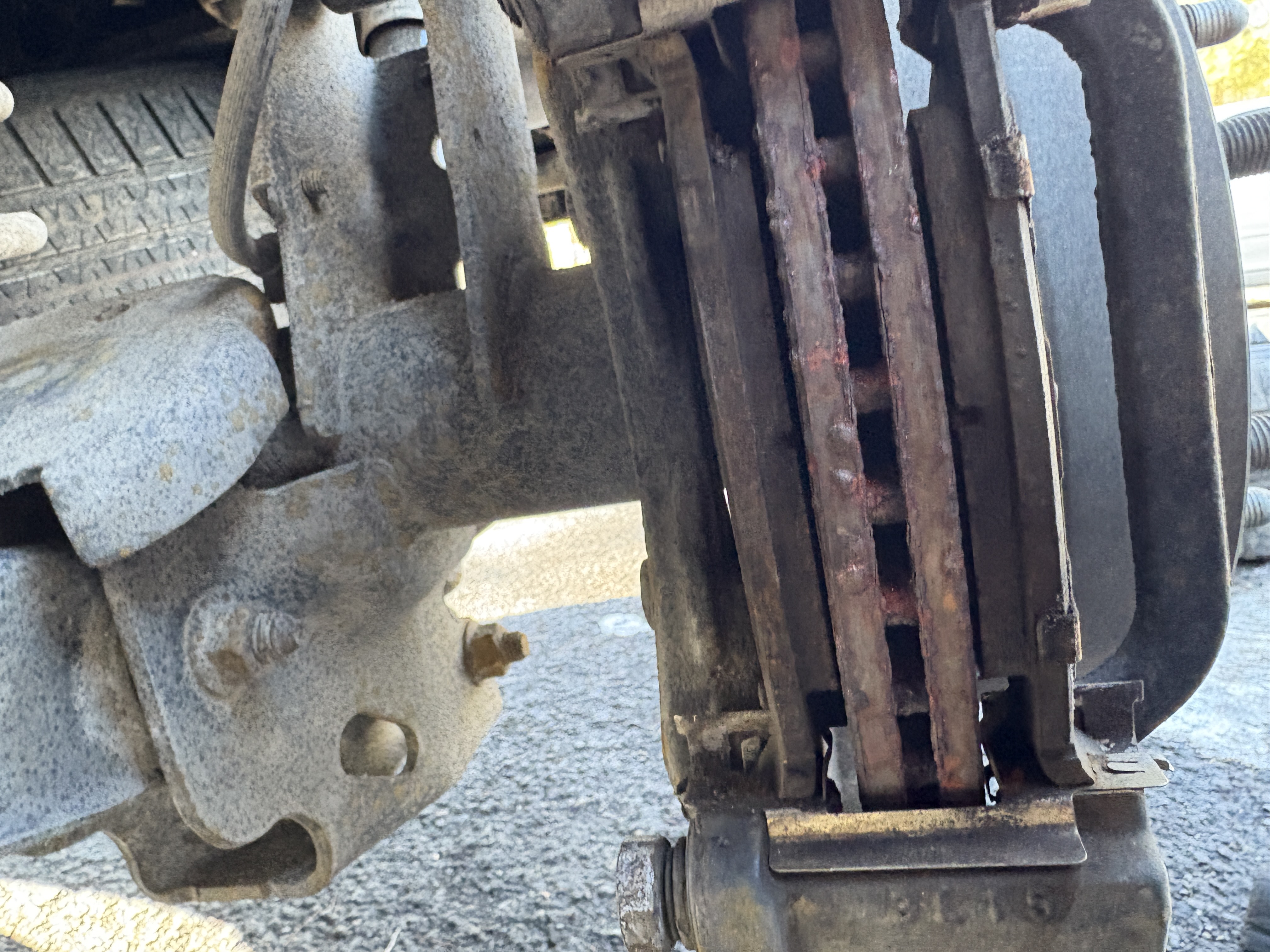 Severely worn brake rotor and caliper before service